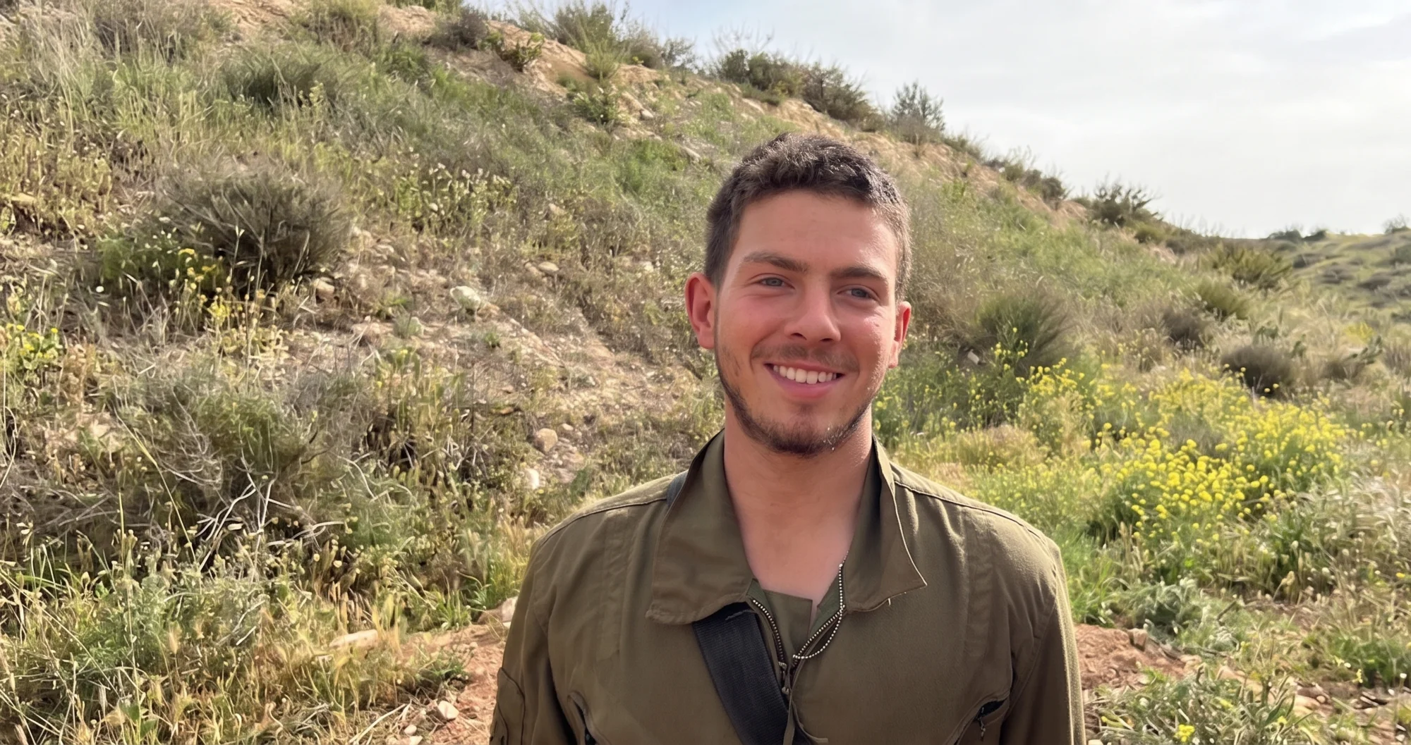 יניב מיכלוביץ ז״ל, מחייך במדי צה״ל על רקע גבעה ירוקה